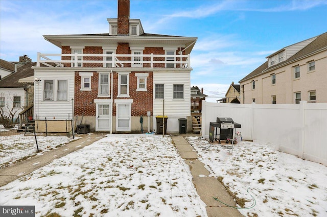 snow covered rear of property featuring a balcony and central air condition unit