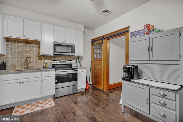 kitchen featuring a barn door, white cabinetry, and appliances with stainless steel finishes