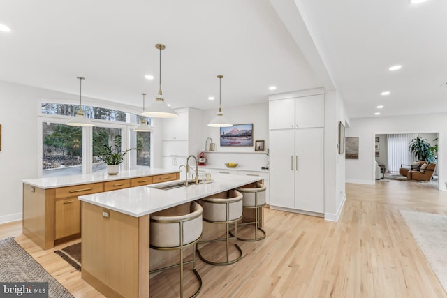 kitchen with white cabinetry, pendant lighting, sink, and a large island with sink