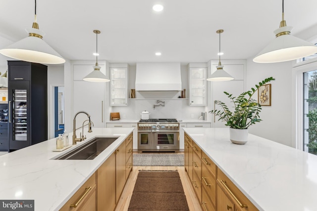 kitchen with sink, double oven range, tasteful backsplash, custom range hood, and decorative light fixtures