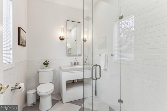 bathroom with vanity, toilet, an enclosed shower, and tile walls