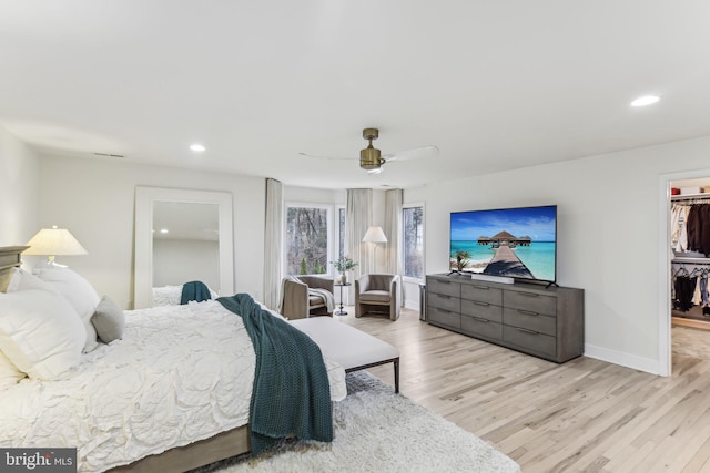 bedroom featuring a spacious closet, light hardwood / wood-style flooring, a closet, and ceiling fan