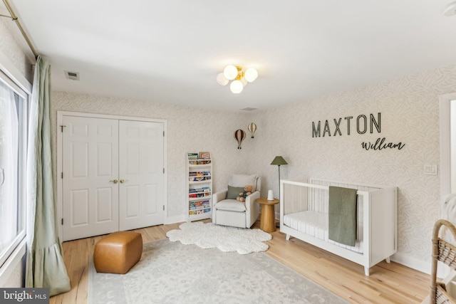 bedroom with a crib, wood-type flooring, and a closet