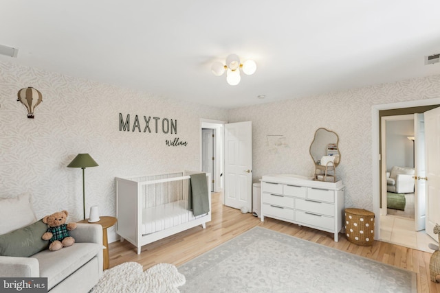 bedroom with a crib and light hardwood / wood-style floors