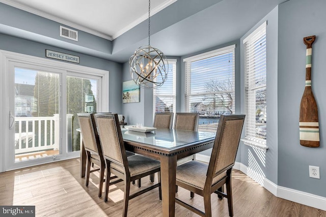 dining room featuring light hardwood / wood-style floors, ornamental molding, and an inviting chandelier