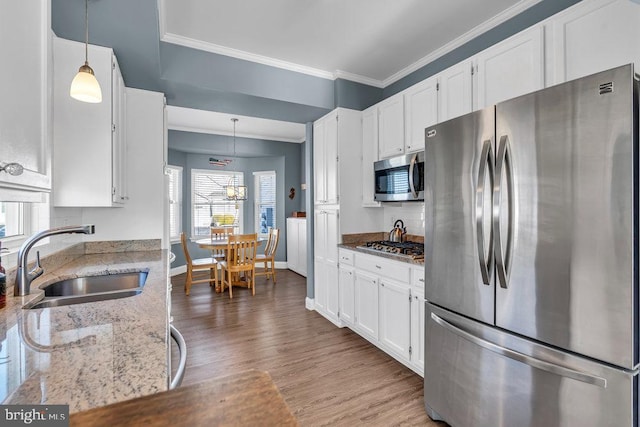 kitchen with white cabinets, sink, decorative light fixtures, light stone counters, and stainless steel appliances