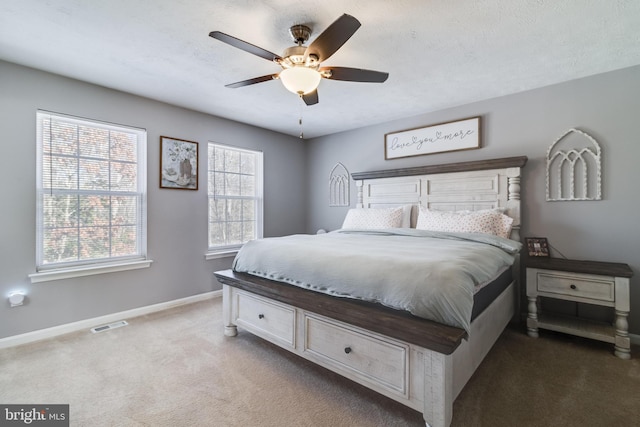 bedroom with dark colored carpet, ceiling fan, a textured ceiling, and multiple windows