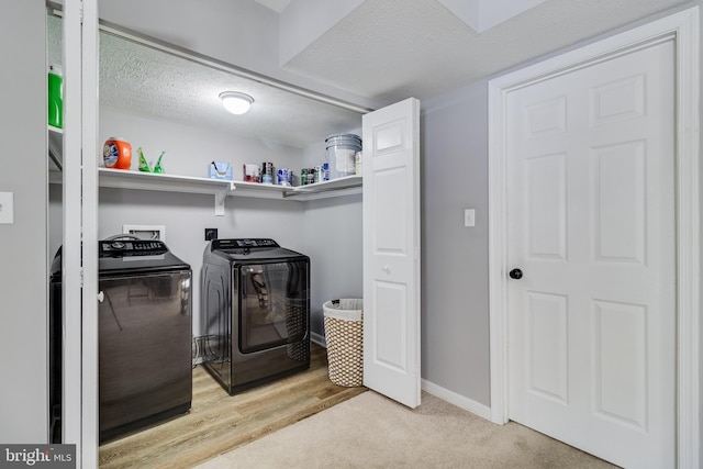 laundry room featuring washing machine and dryer, light carpet, and a textured ceiling