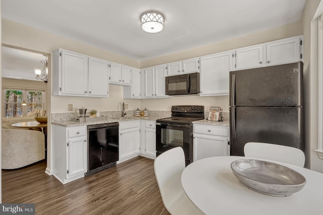 kitchen with black appliances, dark hardwood / wood-style flooring, white cabinets, and sink