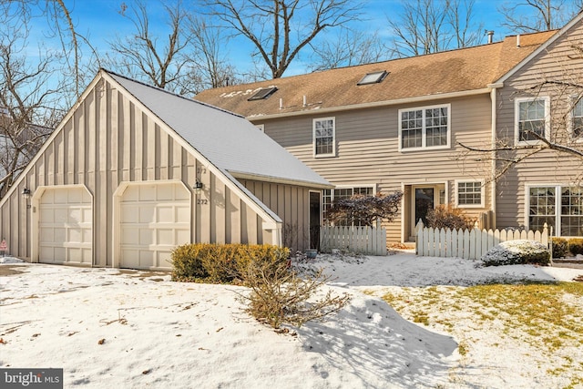 snow covered back of property featuring a garage