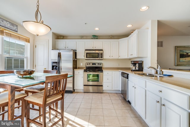 kitchen featuring decorative light fixtures, stainless steel appliances, light tile patterned floors, white cabinetry, and sink