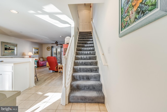 staircase featuring ceiling fan and tile patterned floors