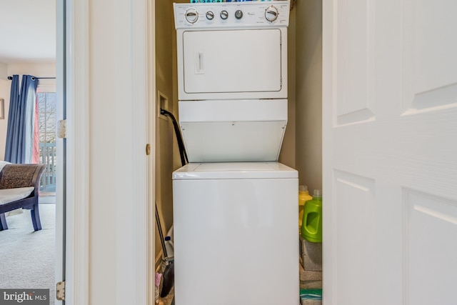 washroom featuring stacked washer / dryer and carpet flooring