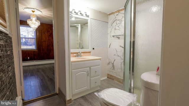 bathroom with wood-type flooring, toilet, vanity, a notable chandelier, and a baseboard radiator