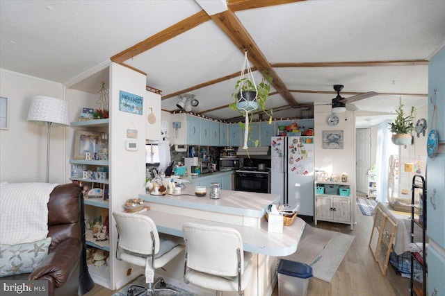 kitchen featuring vaulted ceiling, kitchen peninsula, ceiling fan, white refrigerator, and gas range