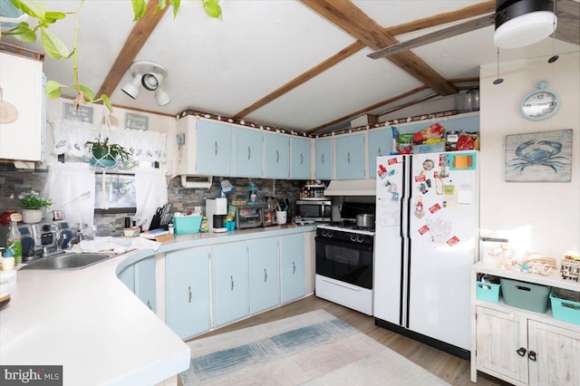 kitchen with white fridge, backsplash, lofted ceiling with beams, blue cabinets, and gas range