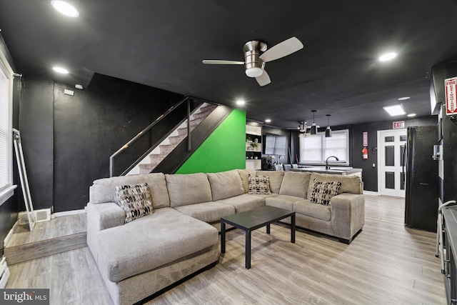 living room featuring ceiling fan, light hardwood / wood-style flooring, and sink