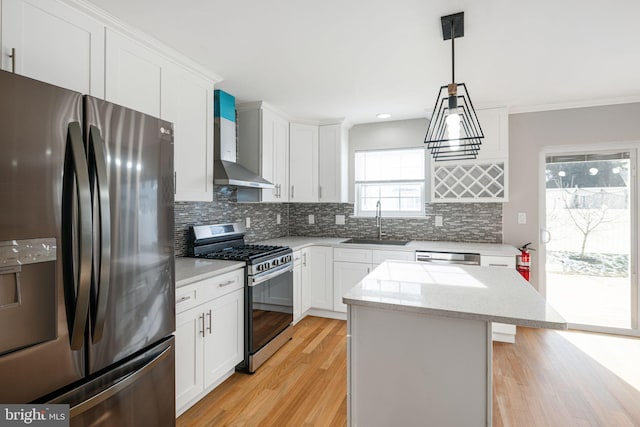 kitchen with wall chimney exhaust hood, pendant lighting, stainless steel appliances, a kitchen island, and sink