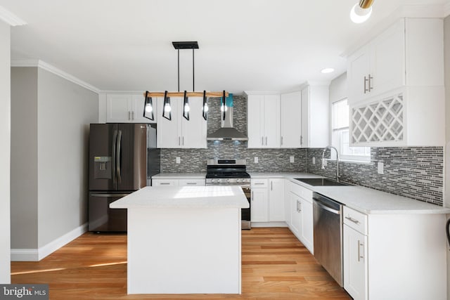 kitchen with appliances with stainless steel finishes, a kitchen island, sink, wall chimney range hood, and decorative light fixtures