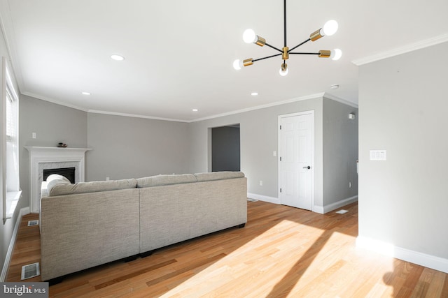 living room featuring a fireplace, an inviting chandelier, light hardwood / wood-style floors, and ornamental molding