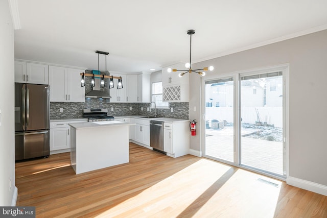 kitchen with a center island, appliances with stainless steel finishes, white cabinetry, and hanging light fixtures