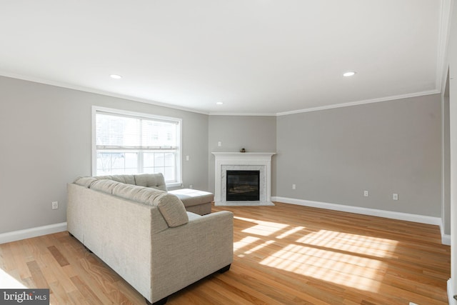 living room with a high end fireplace, ornamental molding, and light hardwood / wood-style floors