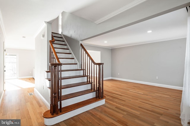 stairs with hardwood / wood-style floors and ornamental molding