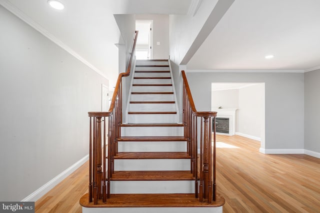 staircase featuring crown molding and wood-type flooring