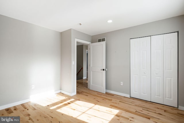 unfurnished bedroom with light wood-type flooring and a closet