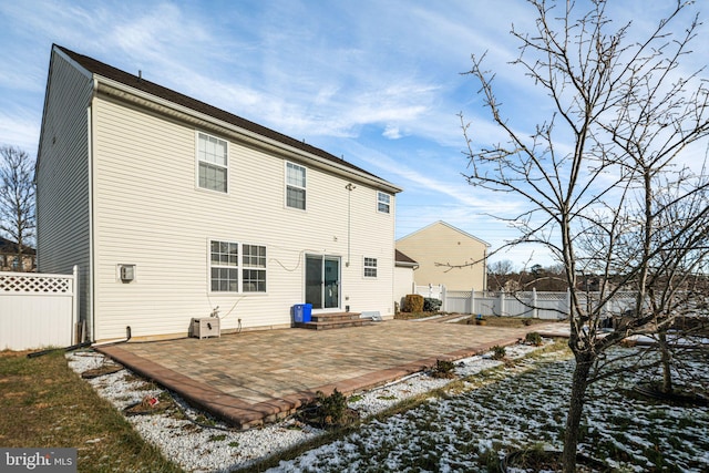 snow covered back of property with a patio