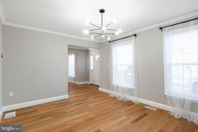 empty room featuring ornamental molding, light hardwood / wood-style flooring, and a chandelier