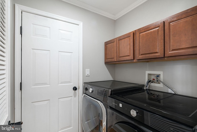 washroom with cabinets, ornamental molding, and washer and clothes dryer