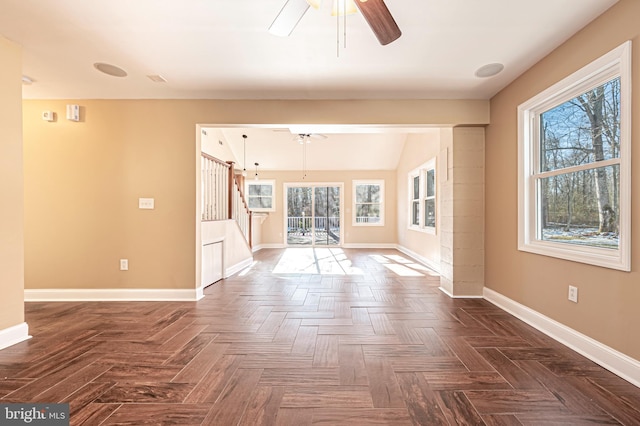 spare room featuring dark parquet flooring, ceiling fan, and a wealth of natural light