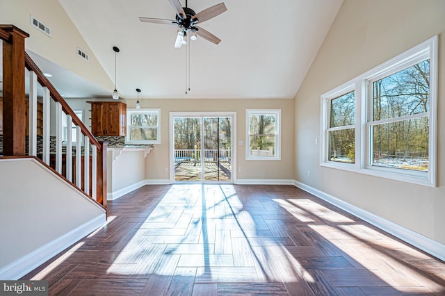 unfurnished living room with lofted ceiling, dark parquet flooring, and ceiling fan