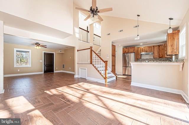 unfurnished living room with light parquet flooring, high vaulted ceiling, and ceiling fan