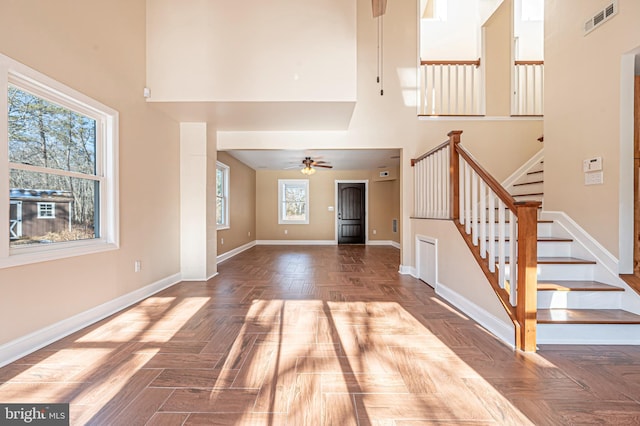 interior space featuring a towering ceiling, ceiling fan, plenty of natural light, and parquet floors