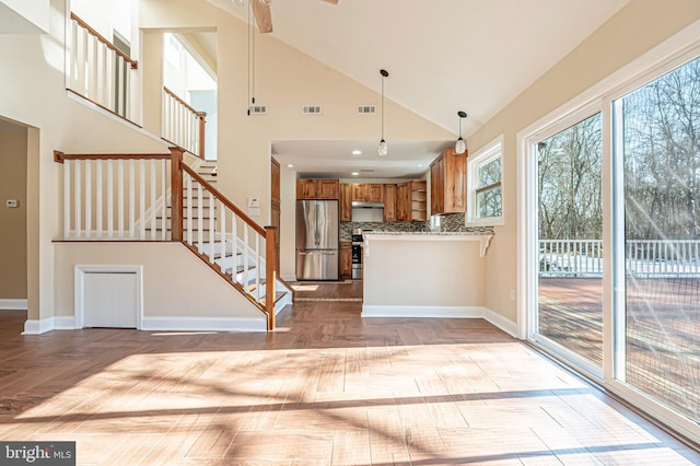 kitchen with hanging light fixtures, light parquet flooring, decorative backsplash, high vaulted ceiling, and appliances with stainless steel finishes