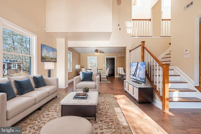 living room with a high ceiling, ceiling fan, and parquet floors