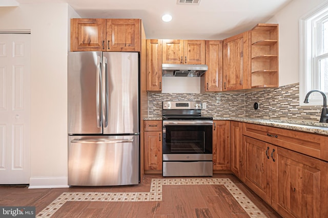 kitchen featuring backsplash, stainless steel appliances, light stone countertops, sink, and light tile patterned flooring