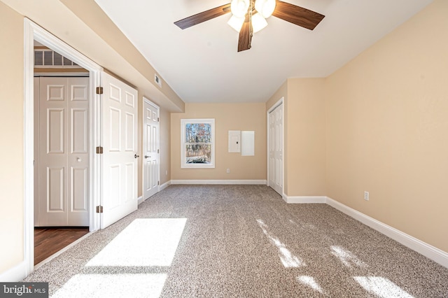 unfurnished bedroom featuring dark carpet, two closets, and ceiling fan