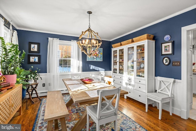 dining room featuring hardwood / wood-style floors, a baseboard heating unit, crown molding, and an inviting chandelier