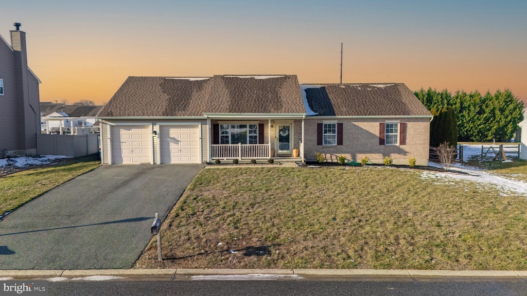 view of front of home featuring a lawn, a porch, and a garage