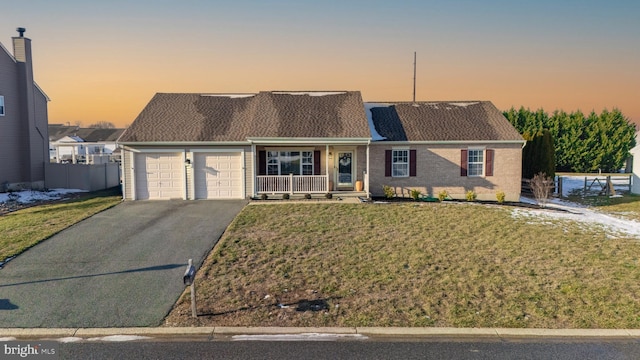 view of front of home featuring a lawn, a porch, and a garage