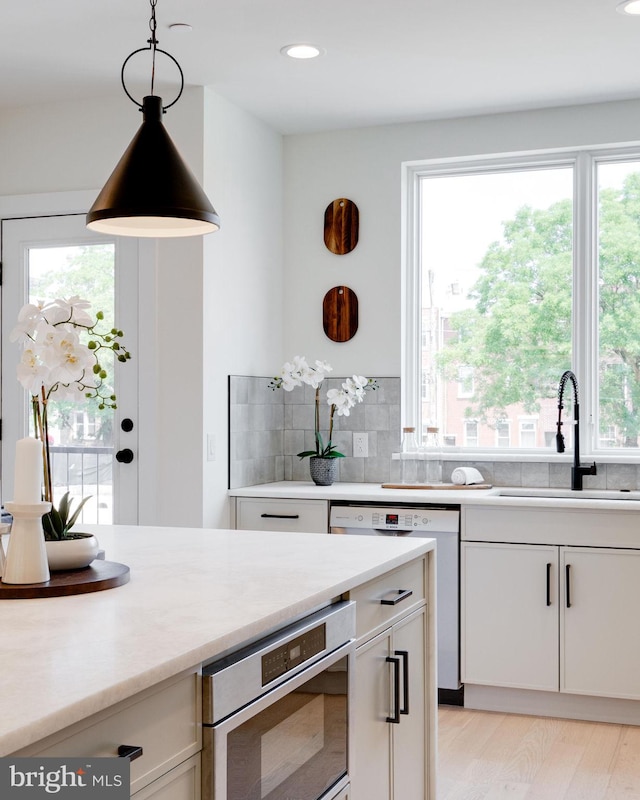 kitchen featuring white cabinetry, sink, a healthy amount of sunlight, and decorative light fixtures