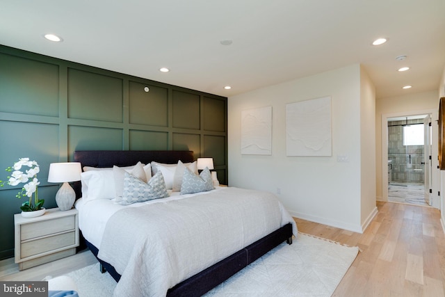 bedroom with ensuite bathroom and light hardwood / wood-style floors