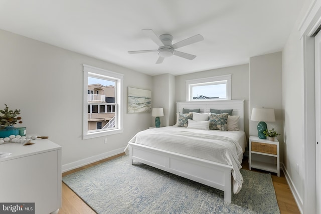 bedroom with ceiling fan, hardwood / wood-style floors, and multiple windows