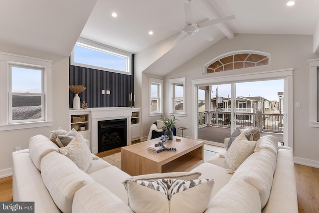 living room with ceiling fan, light hardwood / wood-style floors, lofted ceiling with beams, and a healthy amount of sunlight