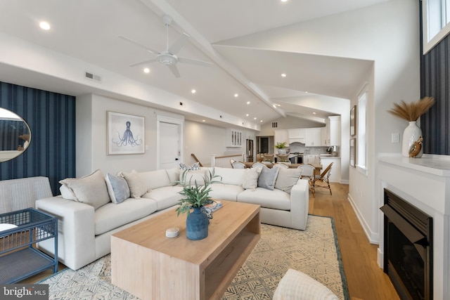 living room with ceiling fan, lofted ceiling with beams, and light hardwood / wood-style floors