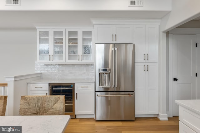 kitchen featuring beverage cooler, high quality fridge, light hardwood / wood-style floors, and white cabinets