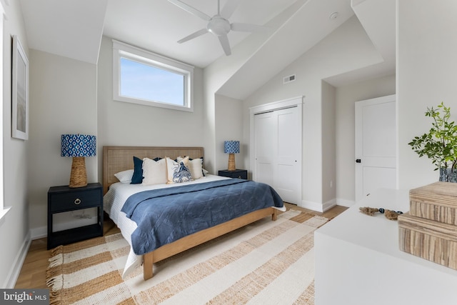 bedroom with ceiling fan, light wood-type flooring, a closet, and lofted ceiling